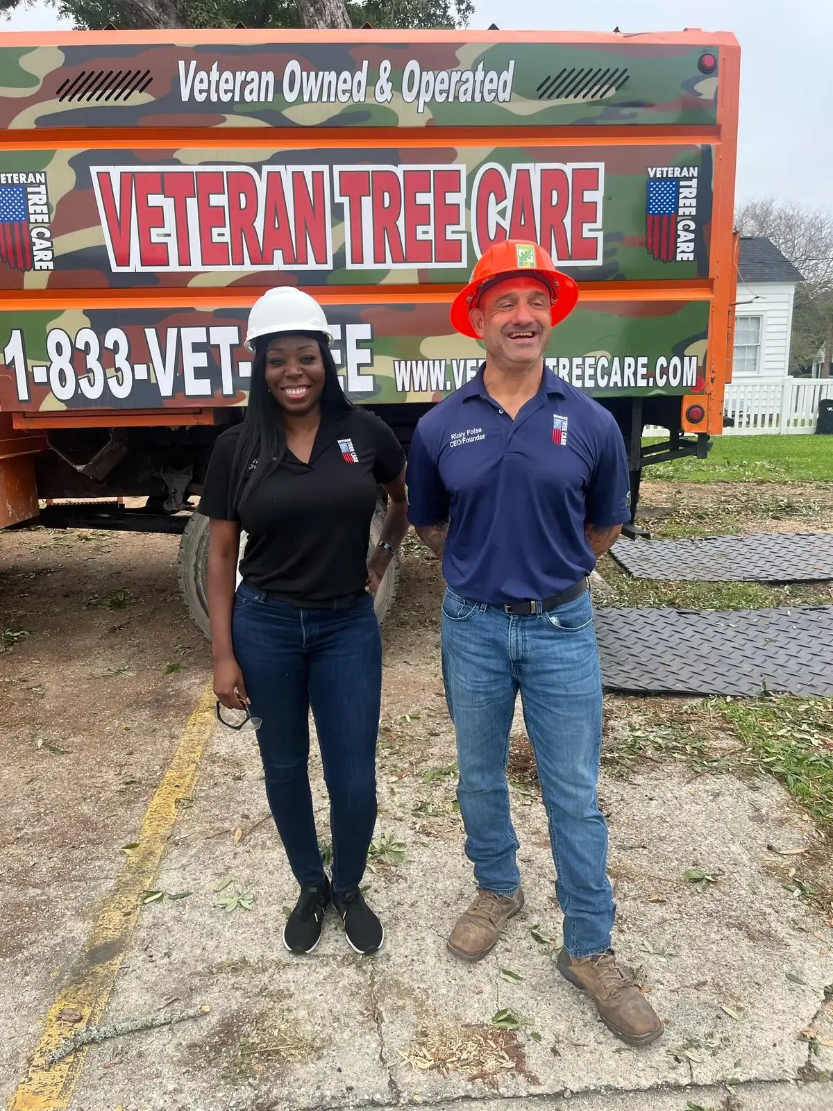Lori Williams and Ricky Folse in hard hats in front of a Veteran Tree Care truck